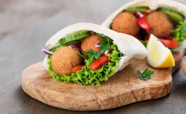 Falafel ve taze sebzeler ahşap masada pide.
