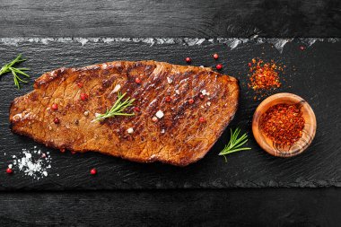 Biberiyeli ızgara biftek, siyah taş tabakta tuz ve biber. Üst görünüm