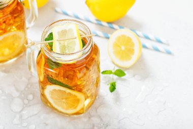 Limon dilimli buzlu çay ve açık gri arkaplanda nane..