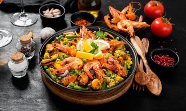 Geleneksel İspanyol deniz ürünleri paella 'sı siyah ahşap bir masada kızartma tavasında..