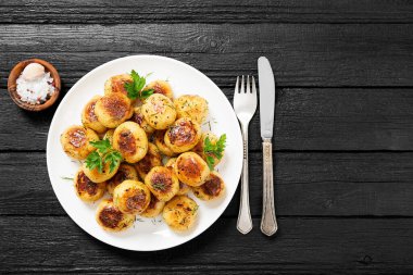 Siyah ahşap zemin üzerinde beyaz tabakta kızartılmış yeni patates..