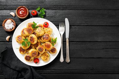 Siyah ahşap zemin üzerinde beyaz tabakta kızartılmış yeni patates..