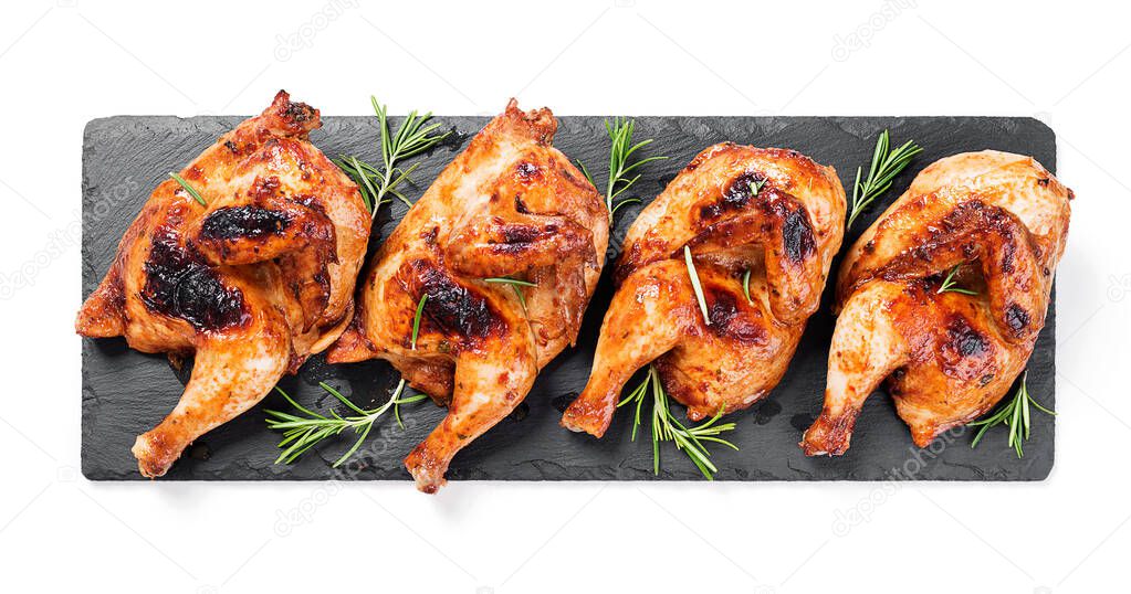 Halves of appetizing grilled juicy chicken with golden brown crust served with lemon slices,barbeque sauce and rosemary. isolated on white background