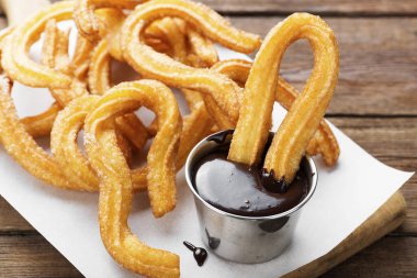 Şeker ve çikolata soslu çurrolar ahşap arka planda.