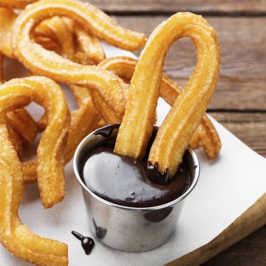 Şeker ve çikolata soslu çurrolar ahşap arka planda.