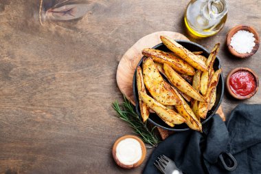 Koyu ahşap arka planda fırında patates ve domates sosu..