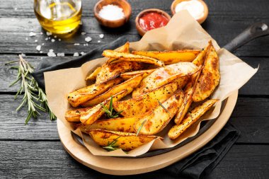 Otlu fırında patates ve siyah arka planda farklı sos..