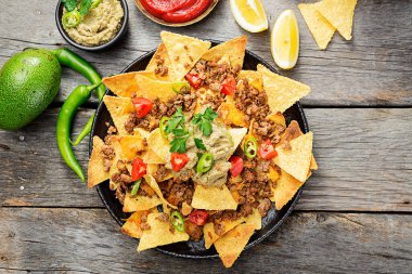 Kızarmış kıymalı mısır cipsi ve ahşap zemin üzerinde guacamole..