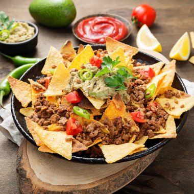 Kızarmış kıymalı mısır cipsi ve ahşap zemin üzerinde guacamole..