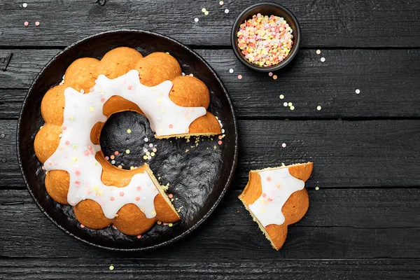 Hausgemachter Bündelkuchen Mit Zuckerguss Und Verzierungen Auf Schwarzem Holzhintergrund — Stockfoto