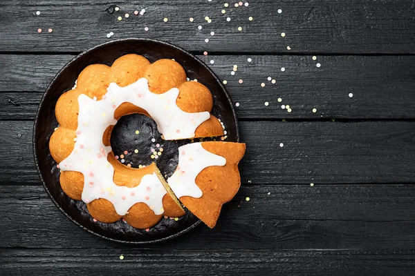 Hausgemachter Bündelkuchen Mit Zuckerguss Und Verzierungen Auf Schwarzem Holzhintergrund — Stockfoto