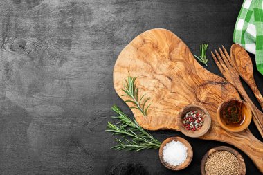 Kesme tahtası, biberiye ve baharatlar siyah ahşap bir masada..