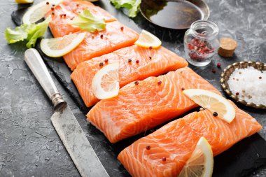 Çiğ somon fileto ve karanlık arka planda yemek pişirmek için malzemeler..