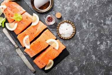 Çiğ somon fileto ve karanlık arka planda yemek pişirmek için malzemeler..