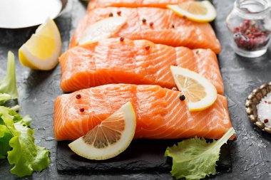 Çiğ somon fileto ve karanlık arka planda yemek pişirmek için malzemeler..