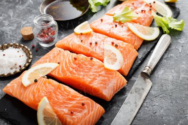 Çiğ somon fileto ve karanlık arka planda yemek pişirmek için malzemeler..
