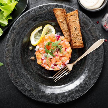 Kırmızı soğanlı somon tartar, avokado, roka ve ekmek tostu..