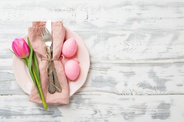Paskalya arkaplanı pembe lale ve beyaz ahşap masa üzerinde renkli yumurtalar..