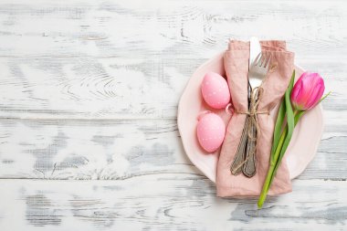 Paskalya arkaplanı pembe lale ve beyaz ahşap masa üzerinde renkli yumurtalar..