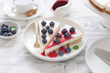 Taze yaban mersini ve böğürtlen soslu peynirli kek beyaz ahşap masada..