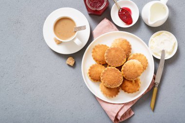 Traditional British Scones with clotted cream, strawberry jam and a cup of coffee.
