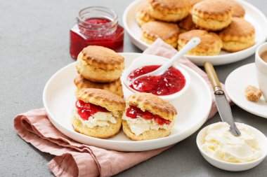 Traditional British Scones with clotted cream, strawberry jam and a cup of coffee.