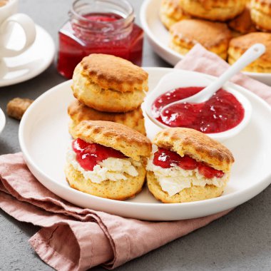 Traditional British Scones with clotted cream, strawberry jam and a cup of coffee.