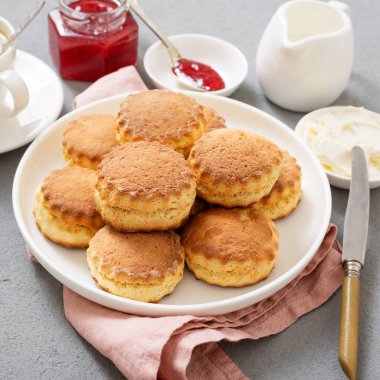 Traditional British Scones with clotted cream, strawberry jam and a cup of coffee.