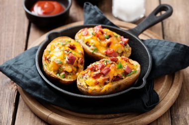 Üzerine pastırma, yeşil soğan ve çedar peyniri konmuş fırında patates..