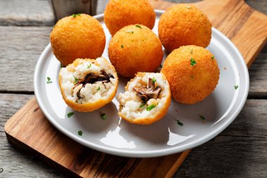 Mantar ve parmesan peyniri ile doldurulmuş ev yapımı Risotto Arancini, domates sosuyla servis edilir..
