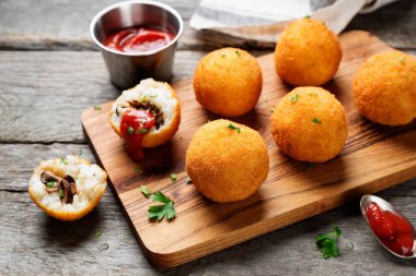 Mantar ve parmesan peyniri ile doldurulmuş ev yapımı Risotto Arancini, domates sosuyla servis edilir..
