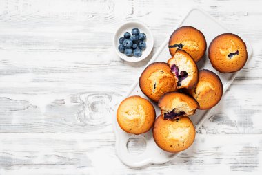 Beyaz ahşap arka planda taze böğürtlenli yabanmersinli kekler.