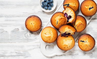 Beyaz ahşap arka planda taze böğürtlenli yabanmersinli kekler.