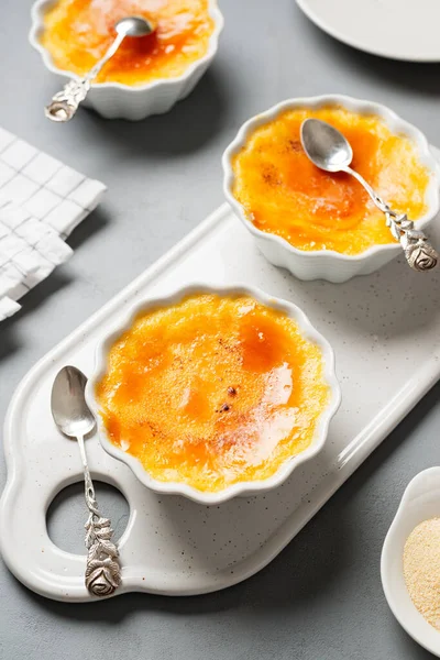 Fresh homemade creme brulee with burnt sugar on gray background.