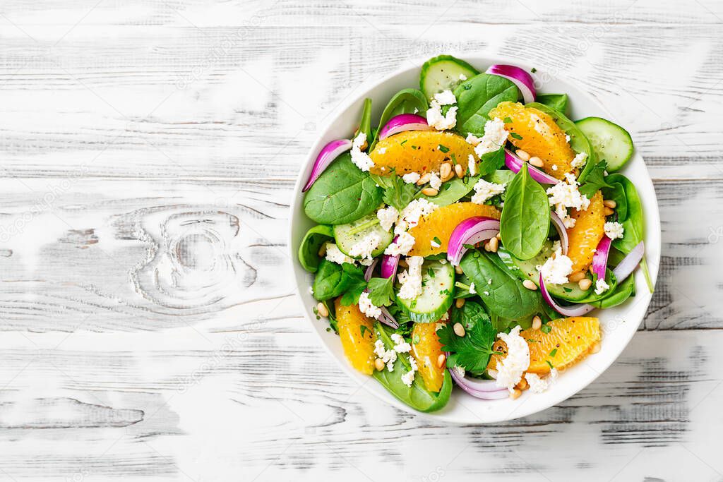 Fresh spinach salad with oranges, feta (ricotta) cheese, red onion and pine nuts .
