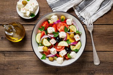 Taze sebzeli, peynirli ve zeytinli klasik Yunan salatası. Sağlıklı yiyecekler. Ahşap arka plan. Üst görünüm