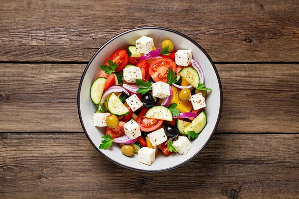 Taze sebzeli, peynirli ve zeytinli klasik Yunan salatası. Sağlıklı yiyecekler. Ahşap arka plan. Üst görünüm