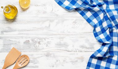 Mavi masa örtüsü ve mutfak malzemeleriyle kaplı beyaz ahşap masa. Yukarıdan bak. Ürün montajı için boş masa örtüsü. Metnin için boş yer