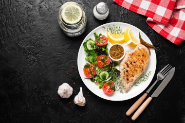 Taze sebze salatasıyla ızgara tavuk göğsü. Sağlıklı yemek, keto diyeti, diyet öğle yemeği konsepti. Siyah taş arkaplanda üst görünüm