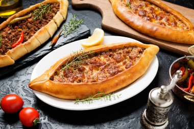 Geleneksel Türk mutfağı. Türlü pizza. Biftekli Pide ve siyah taşlı arkaplanda peynirli pide.