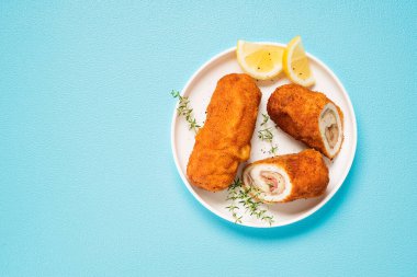 Geleneksel Fransız mutfağı çıtır çıtır, kremalı tavuk cordon bleu mavi arka planda. Üst Manzara. Metin için boşluk