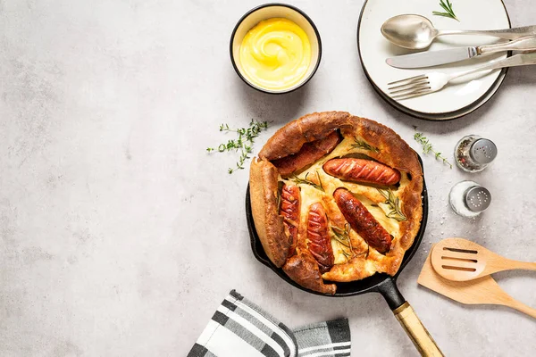 Toad in the hole, Sausage Toad, traditional English dish of sausages in Yorkshire pudding batter. Light gray background, top view. Space for text