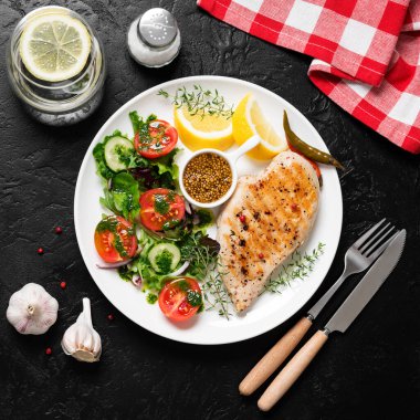 Taze sebze salatasıyla ızgara tavuk göğsü. Sağlıklı yemek, keto diyeti, diyet öğle yemeği konsepti. Siyah taş arkaplanda üst görünüm
