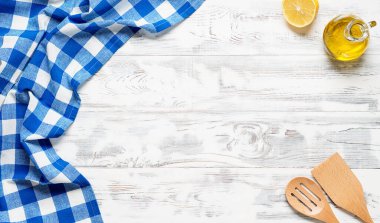 Mavi masa örtüsü ve mutfak malzemeleriyle kaplı beyaz ahşap masa. Yukarıdan bak. Ürün montajı için boş masa örtüsü. Metnin için boş yer