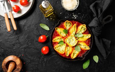 Parmesan peyniri ve taze fesleğenle servis edilen ıspanak ve ricotta ile doldurulmuş makarna kabukları. Sağlıklı vejetaryen yemek tarifi. Siyah arka plan. Üst görünüm
