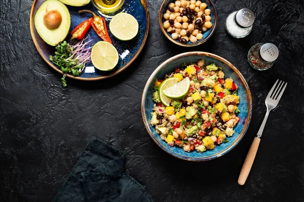 Healthy quinoa black bean salad with mango and avocado. Perfect for spring, summer, fall or winter. Black stone background, top view.