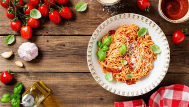 Lezzetli iştah açıcı klasik İtalyan spagettisi domates soslu, parmesan peynirli ve taze fesleğen yapraklı. Ahşap arkaplan, üst manzara