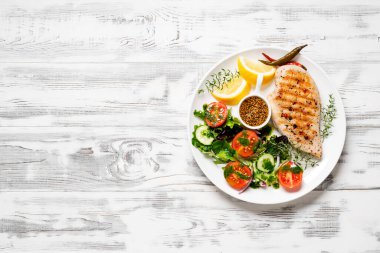 Taze sebze salatasıyla ızgara tavuk göğsü. Sağlıklı yemek, keto diyeti, diyet öğle yemeği konsepti. Beyaz ahşap arkaplanda üst görünüm.