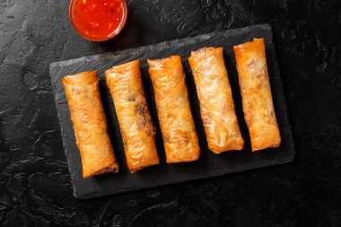 Kırmızı lahana ile doldurulmuş taze kızarmış börekler ve tatlı biber sosuyla servis edilen havuç. Siyah arkaplan, üst görünüm .