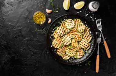 Siyah tabakta sarımsak soslu ızgara kabak dilimleri..